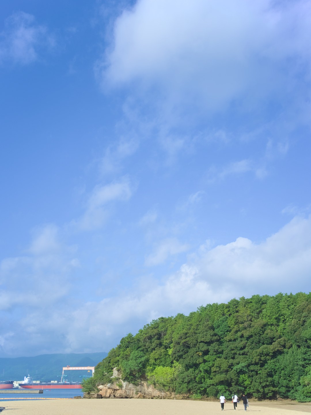 イマリンビーチの砂浜と、浜を歩く生徒たち